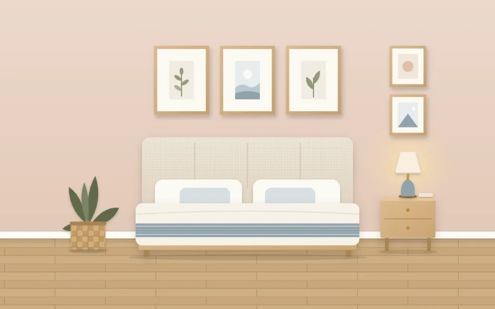 Three matching oak frames with wide white mats in a row above a linen headboard, and two small frames above a nightstand lamp