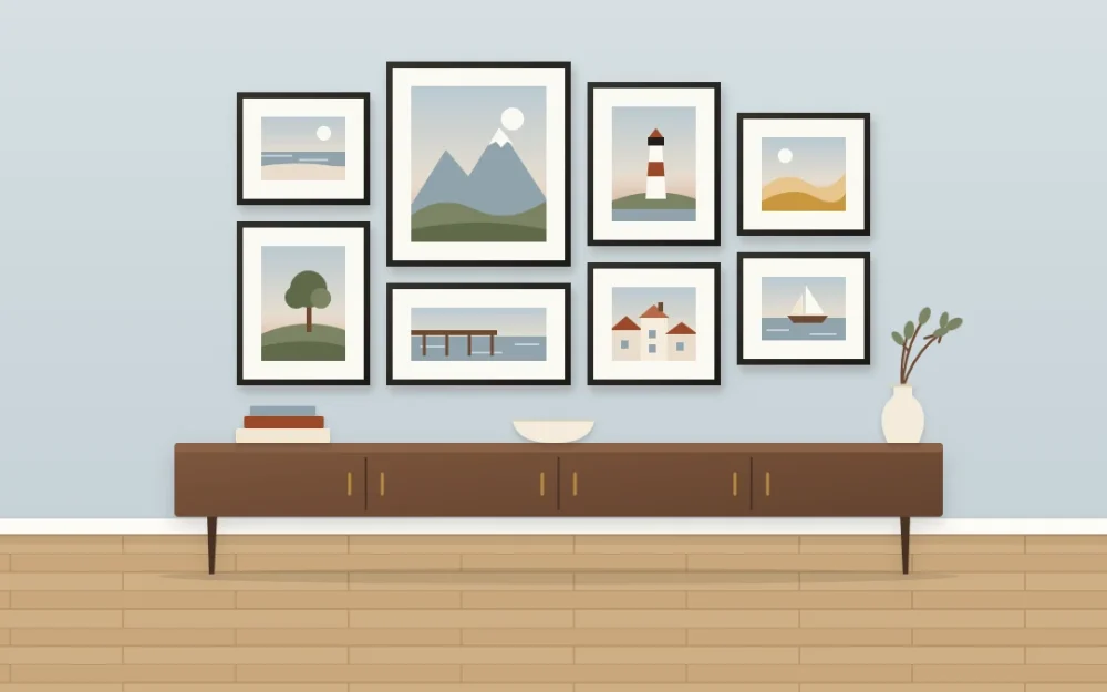 Eight thin black frames with white mats holding simple landscape scenes, including a beach, mountains and a lighthouse, above a console